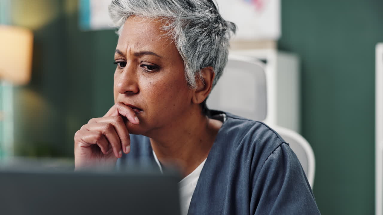 A concerned nurse looking at a computer