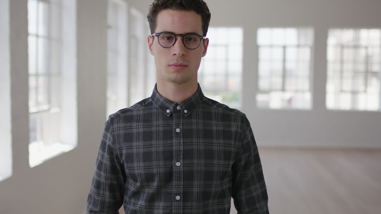 portrait of attractive young hipster man looking serious at camera in new apartment