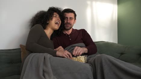 playful couple enjoying popcorn and movie at home