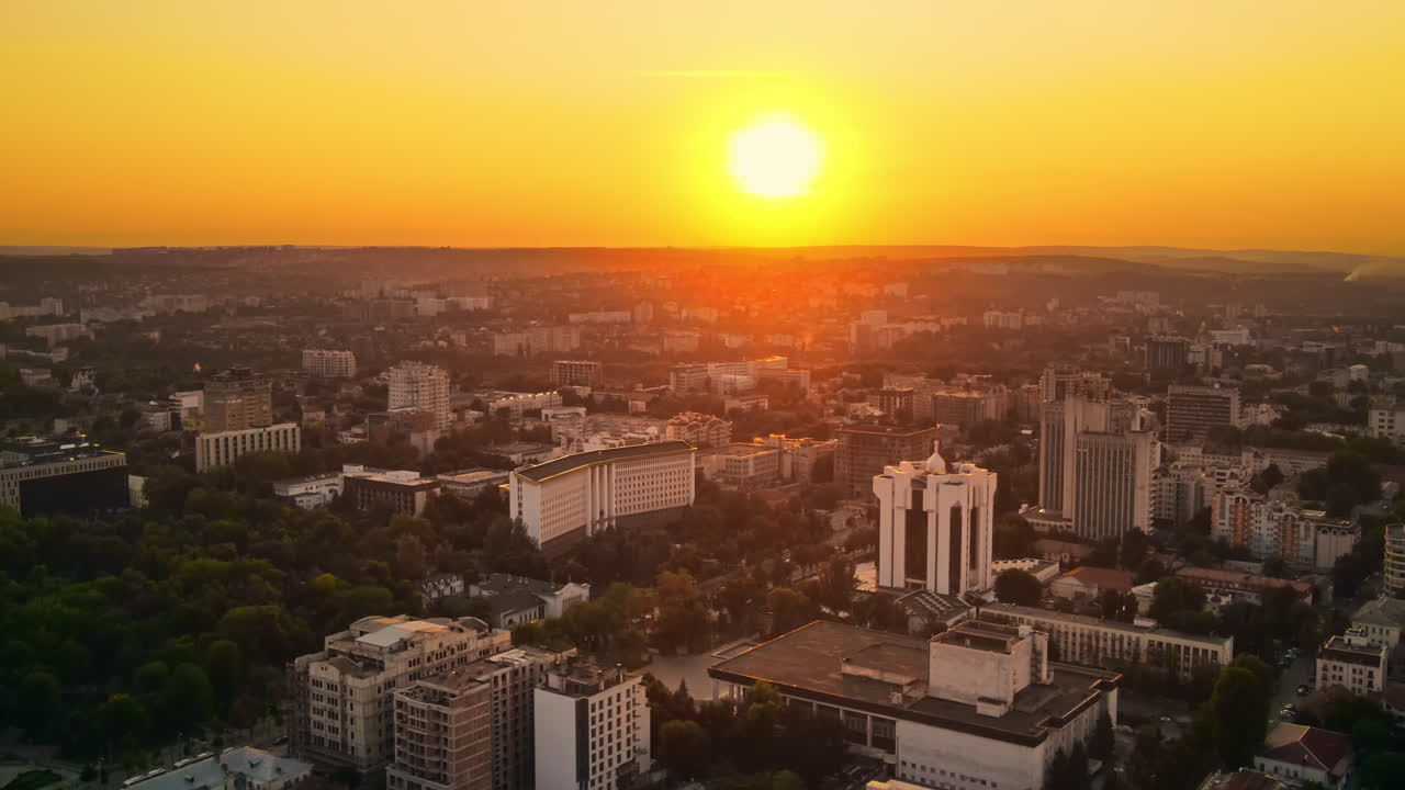 Vista aérea de drone do centro de Chisinau ao pôr do sol. Vista panorâmica de vários edifícios, Parlamento, Presidência, estradas com carros em movimento e árvores exuberantes. Moldávia