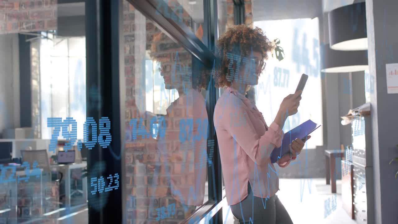 Processing data over happy biracial casual businesswoman using smartphone in office corridor