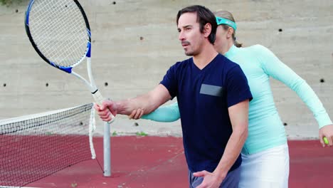 coach assisting man in playing tennis