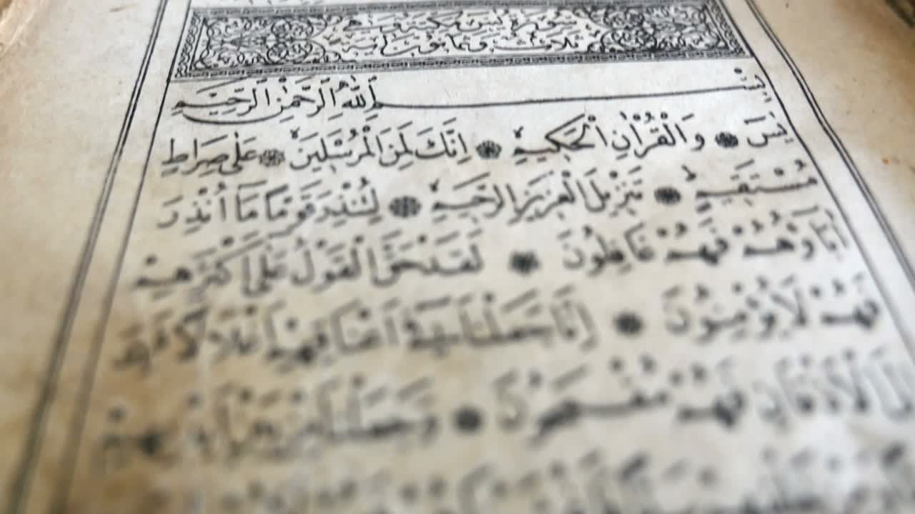 Footage of an old Quran, the shot is moving from the bottom to the top