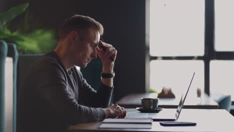 thoughtful 30s man thinking of problem solution working on laptop. serious doubtful male professional looking away at laptop considering market risks making difficult decision sitting at desk