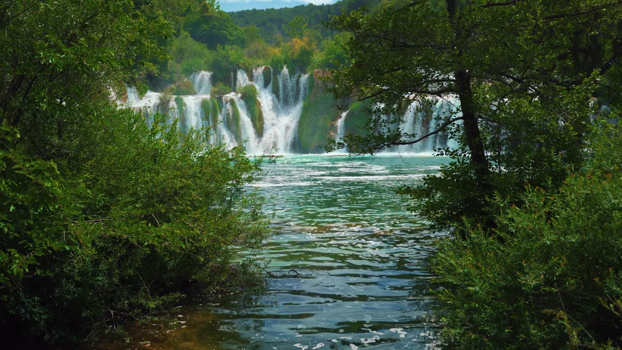 Cascate panoramiche che scorrono attraverso una lussureggiante foresta verde nel Parco nazionale di Krka, Croazia, al rallentatore