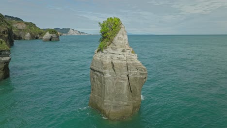 natural limestone sea stack column near shore of new zealand, aerial