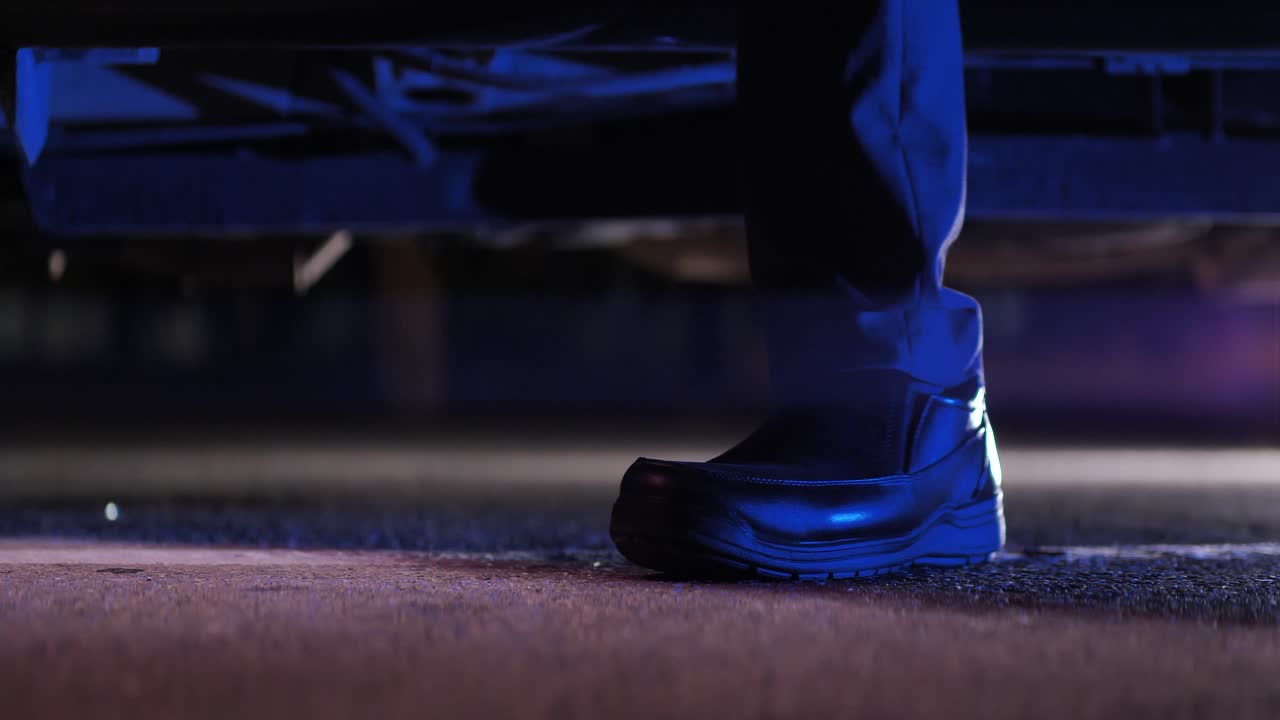 el hombre sale del auto en el estacionamiento por la noche, el zapato se cierra