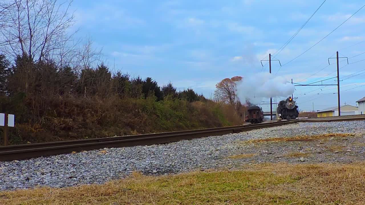 겨울날 불어오는 증기에 접근하는 골동품 증기 엔진의 낮은 각도