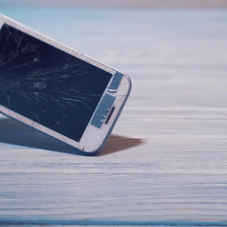 modern white touchscreen phone is falling on the floor and crashes isolated on the wooden background floor. broken smartphone on the grey surface.