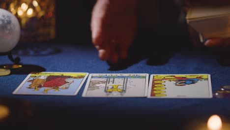 primer plano de una mujer dando una lectura de cartas de tarot en una mesa a la luz de las velas 17
