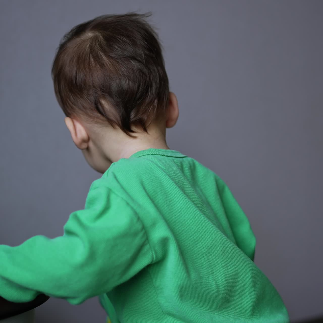 Bambino dai capelli scuri che tiene un giocattolo in bocca. Bambino piccolo che gioca con i giocattoli nella stanza