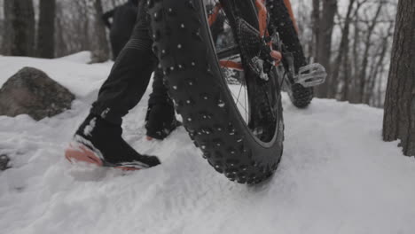 lady rider walking fat bike up a snowy hill