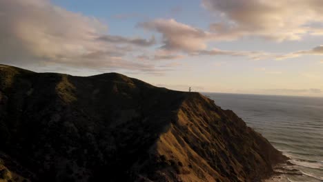 Faro-En-La-Península-De-Aupouri-Con-El-Mar-De-Tasman-Al-Atardecer-En-Cabo-Reinga,-Northland,-Nueva-Zelanda