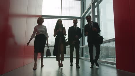 dolly shot of businesspeople female and male walking in office center hall talking