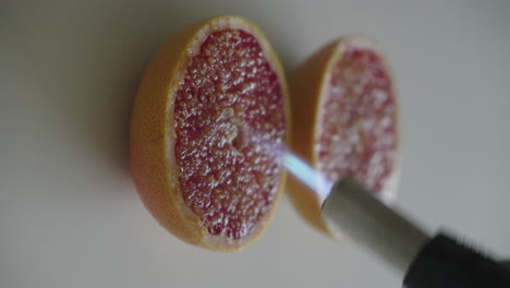 caramelizing sugar on the top of grapefruit using gas torch close up 4k vertical