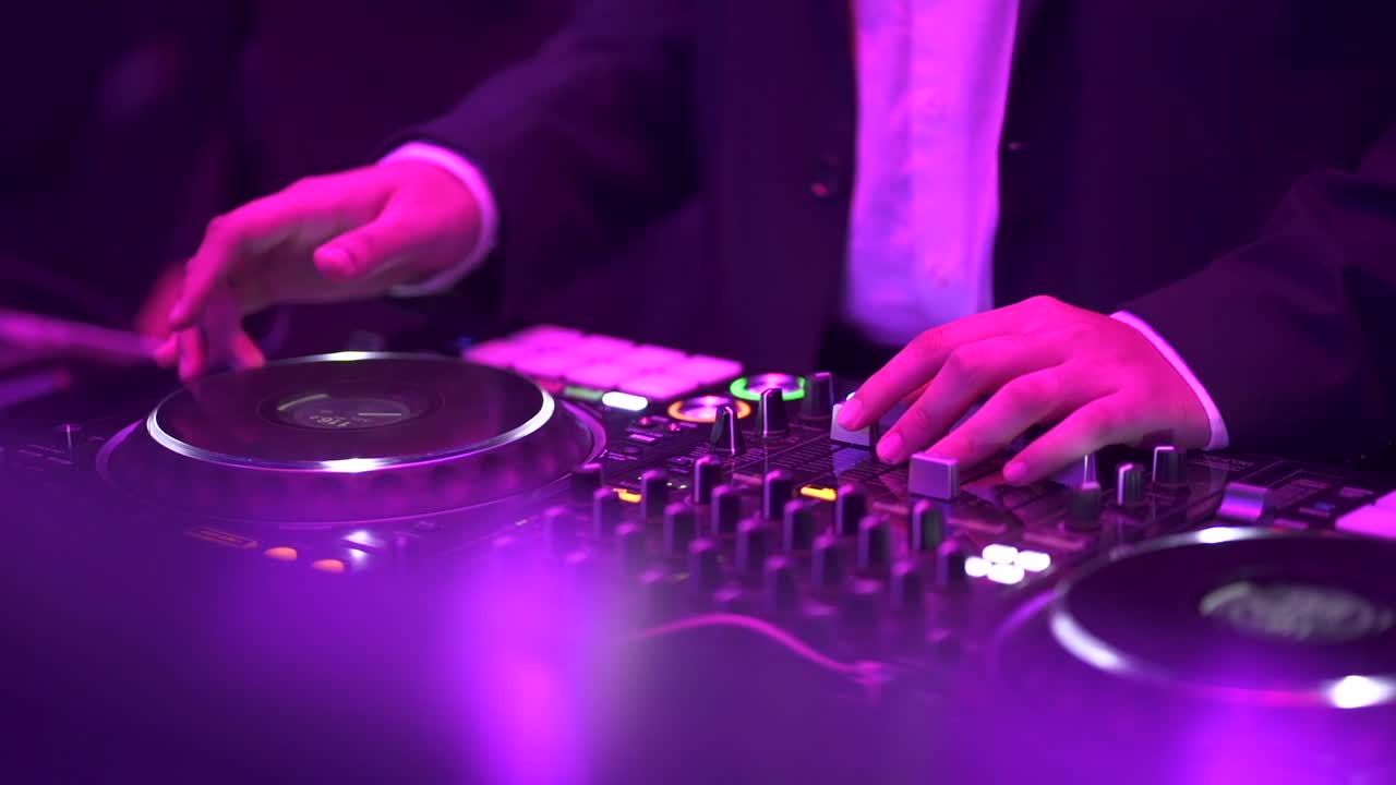 manos de dj moviendo controles en la cubierta de discos en el club nocturno