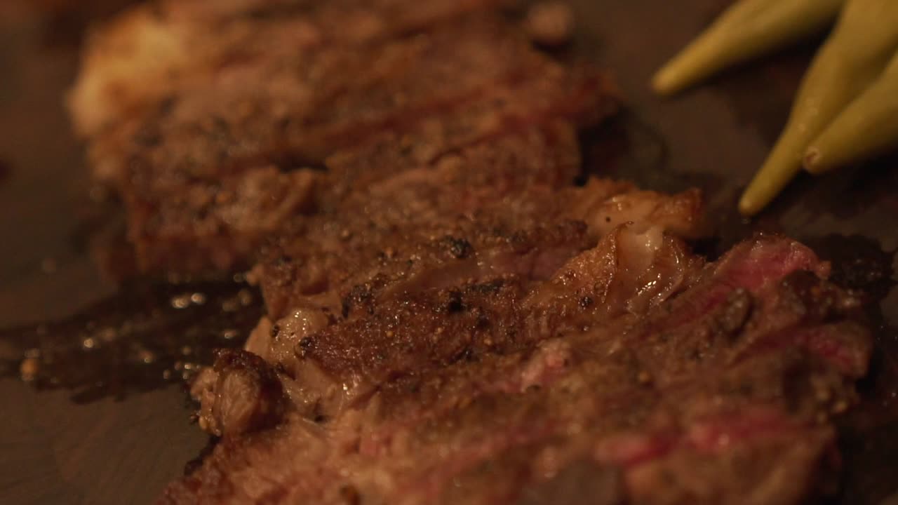 Slow motion tilt down shot of grilled and sliced rare wagyu beef steak on a wooden cutting board in HD 1080p23.98p