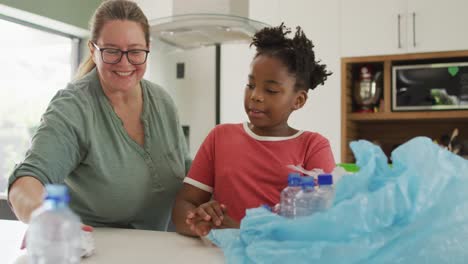 Happy-caucasian-woman-and-her-african-american-daughter-sorting-waste-together