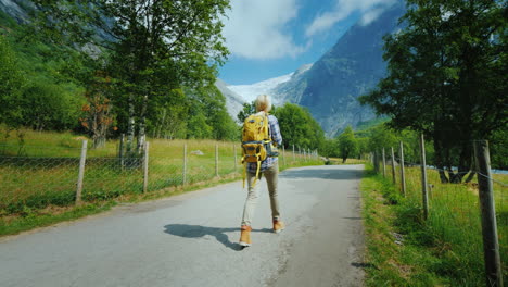 una mujer camina por el camino hacia el glaciar briksdal en noruega una vista trasera viajando en escandinavia