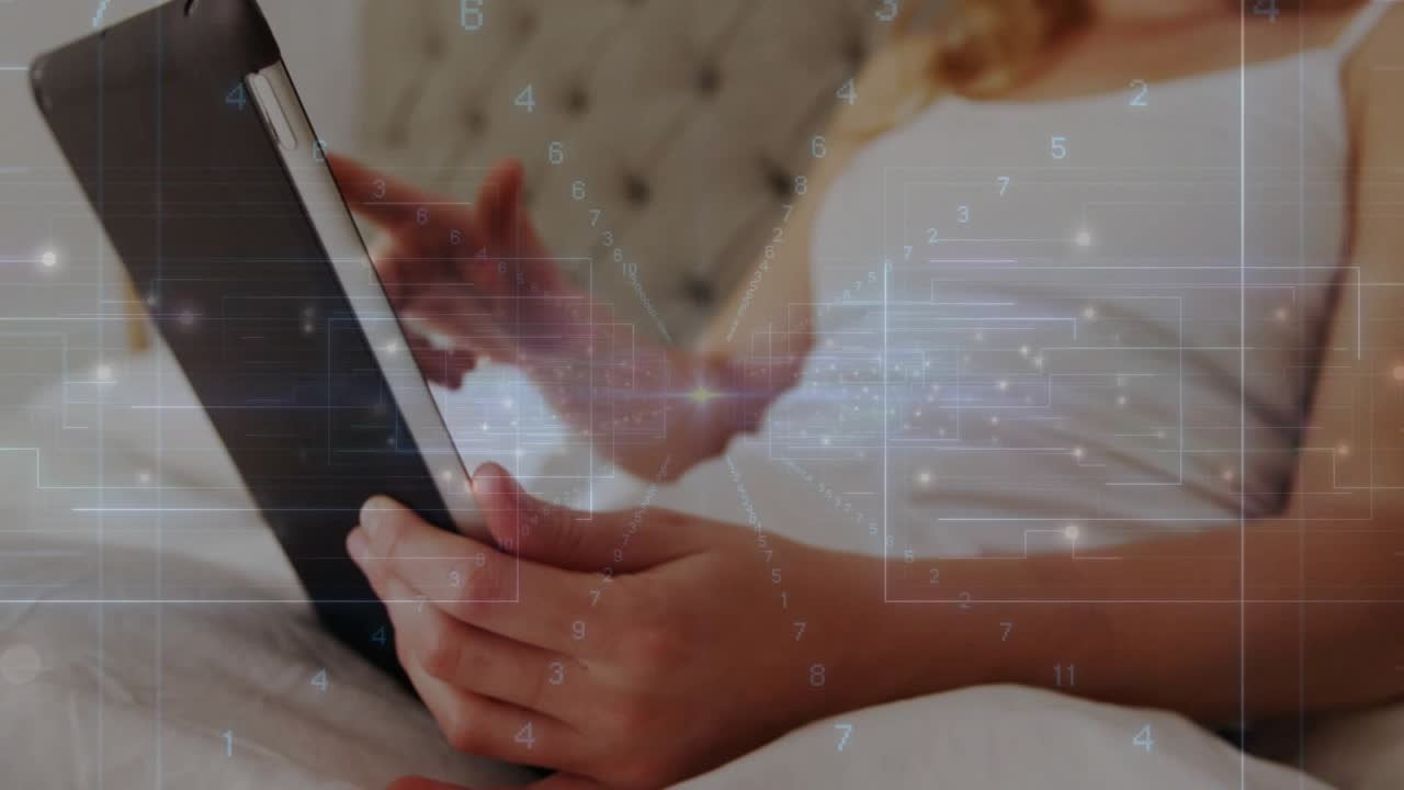 Woman reclining on bed holding black tablet, finger tapping, initiating tech overlay, viewing data