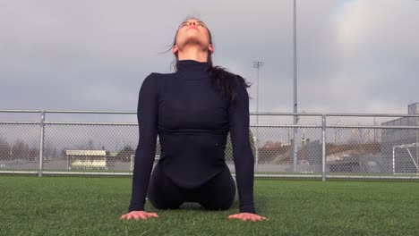 young athletic woman practicing yoga at the sports field, front, slomo