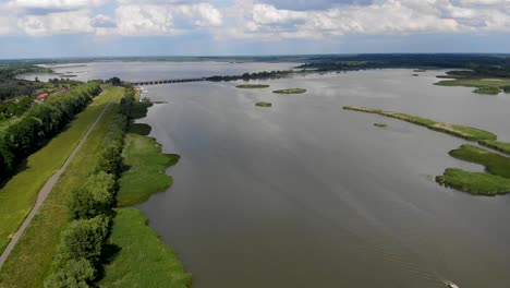 Aerial-view-of-a-river-with-a-small-white-boat-and-green-patch-of-islands