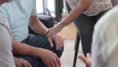 distressed diverse seniors holding hands, talking in group therapy session, unaltered, slow motion