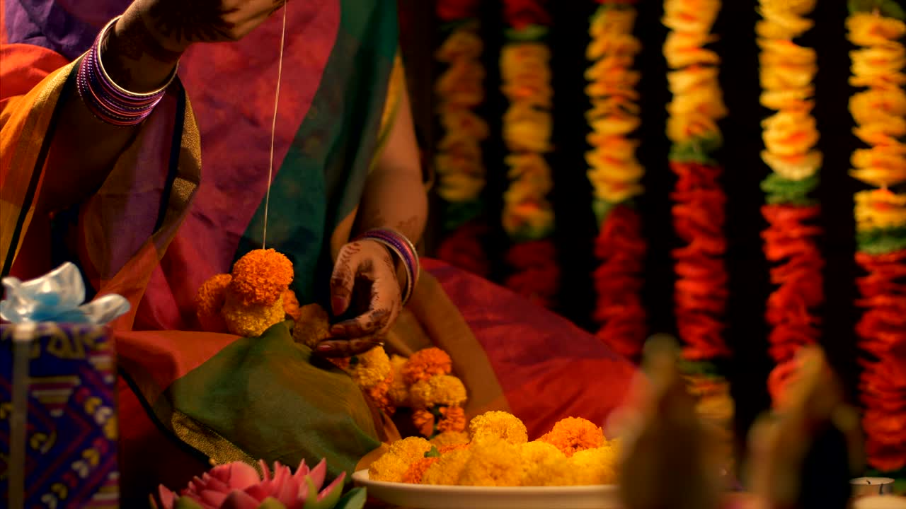 Diwali celebration - Woman / female making the flower garland for diwali / durga puja