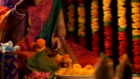 diwali celebration - woman / female making the flower garland for diwali / durga puja