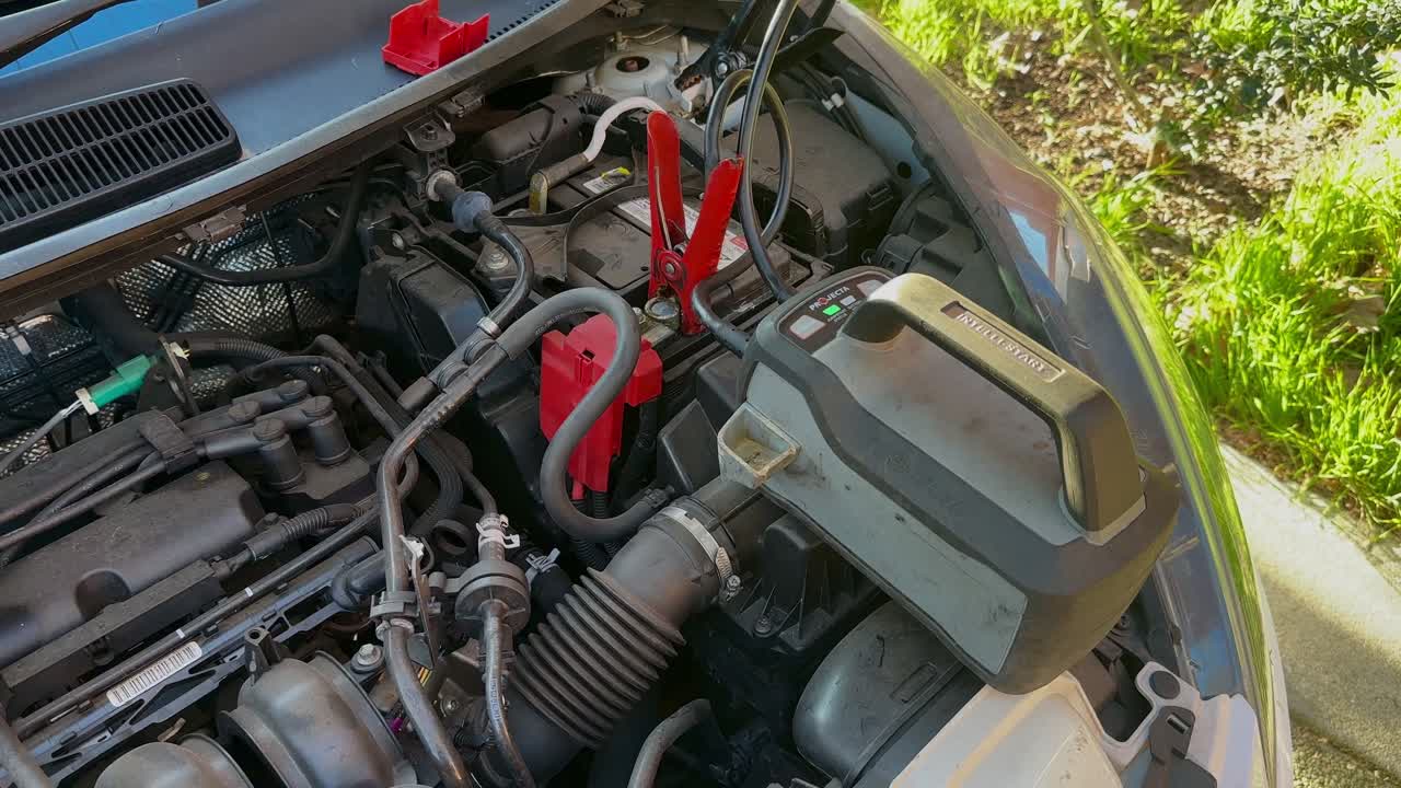 Car battery recharging small engine Ford Fiesta by roadside grass