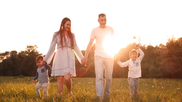 famiglia felice il loro uomo con due figli che cammina sul campo al tramonto nella luce del tramonto in estate in tempo caldo.