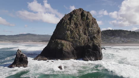 clear blue water smashes into haystack rock at cannon beach