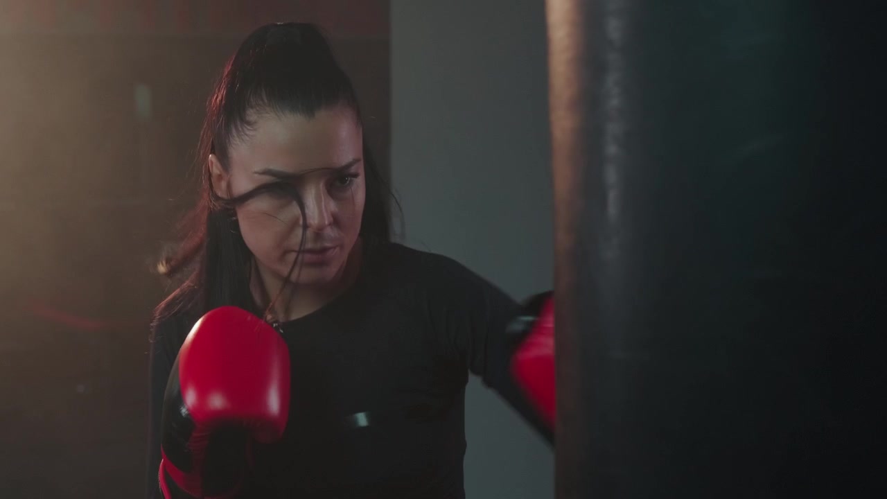 Donna determinata che si allena con il sacco da boxe in palestra