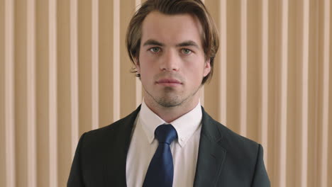 close up portrait of attractive young successful businessman looking serious at camera wearing suit