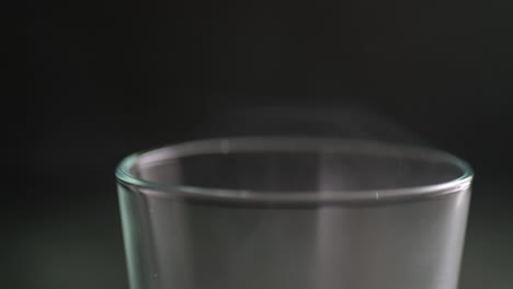 macro de primer plano de un borde de un vaso de vapor con una bebida caliente