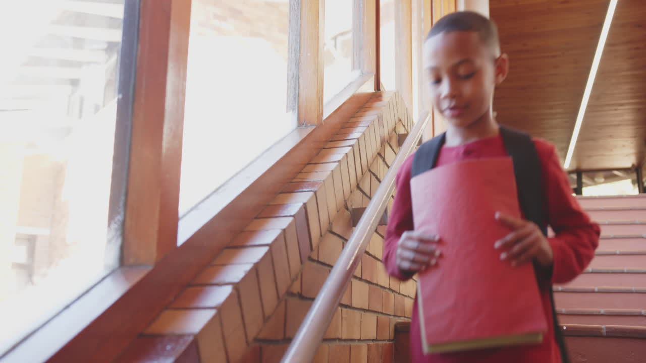 In school, boy with backpack waving at window, smiling and looking outside