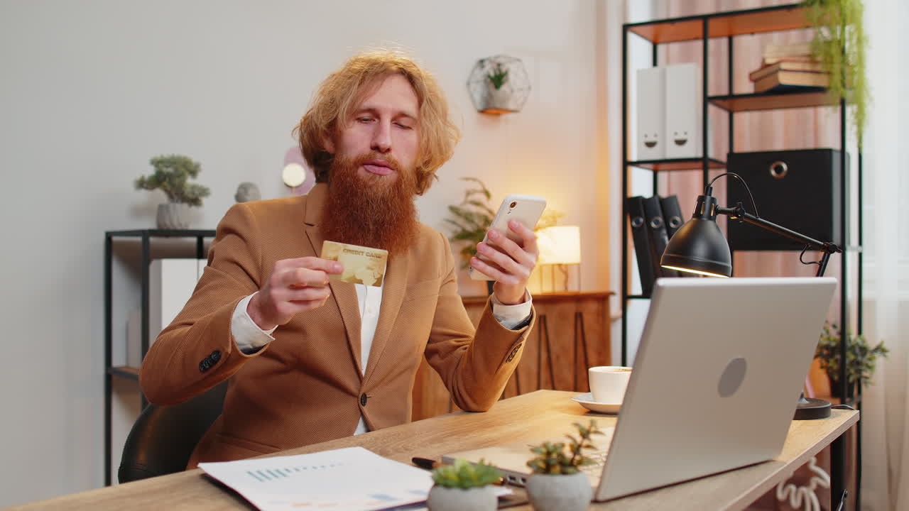 Geschäftsmann nutzt Bank-Kreditkarte und Smartphone für Online-Shopping-Zahlungen im Homeoffice