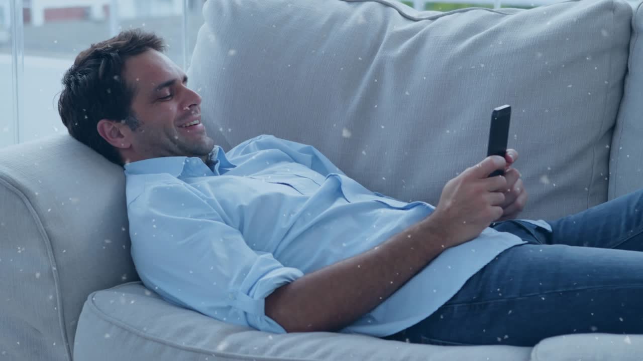 Animazione di neve che cade su un uomo caucasico felice che usa uno smartphone.