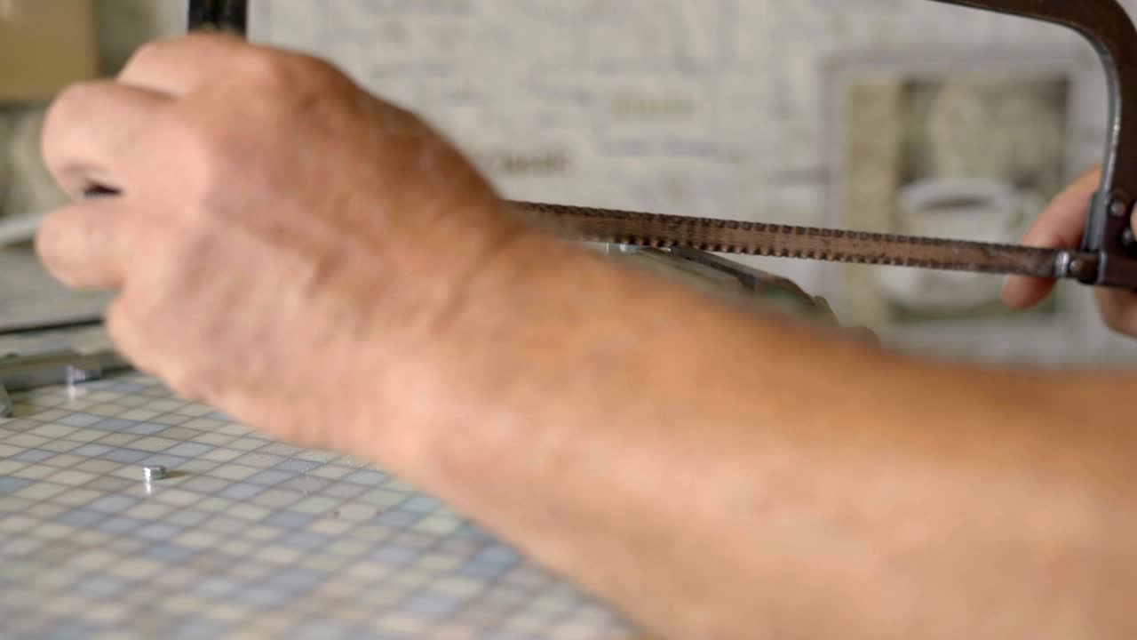 en primer plano, un anciano agarra el perno de metal y lo corta con una sierra de metal.