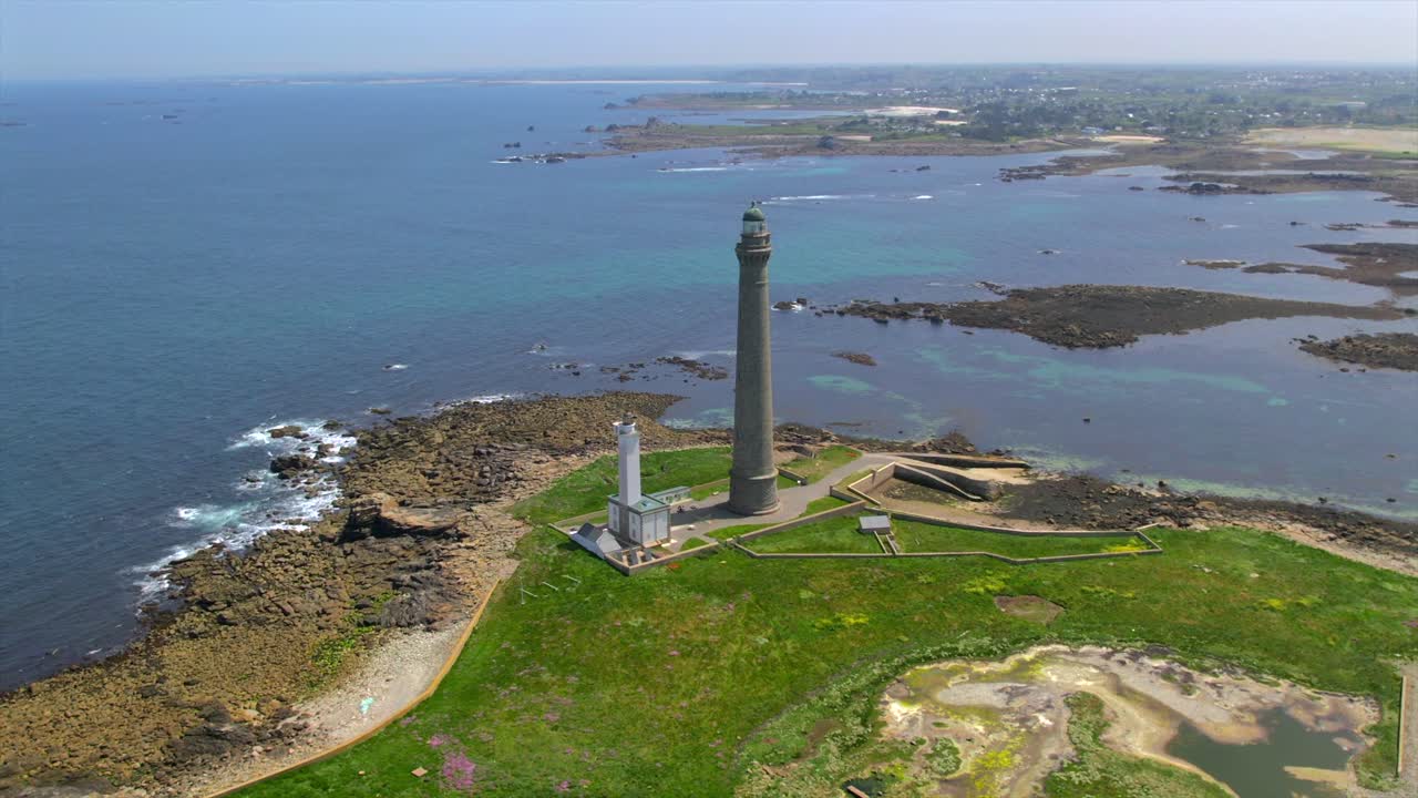 High-angle aerial view of Phare de l’Île Vierge lighthouse and surrounding rocky coastline in Brittany, France, highlighting the green coastal landscape and expansive Atlantic Ocean.