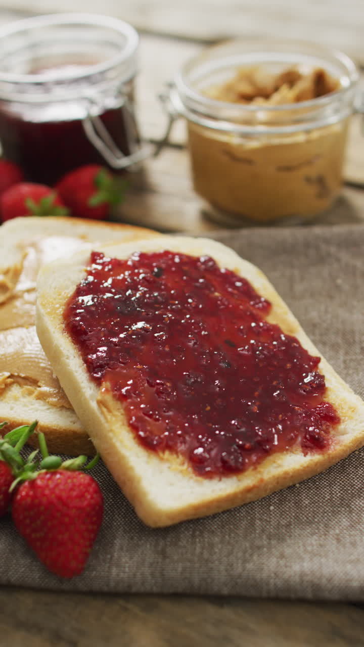 Vertical video of sandwiches with jam and strawberry lying on fabric