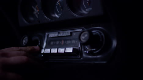 man hand playing with an old corvette radio, moving dials and buttons