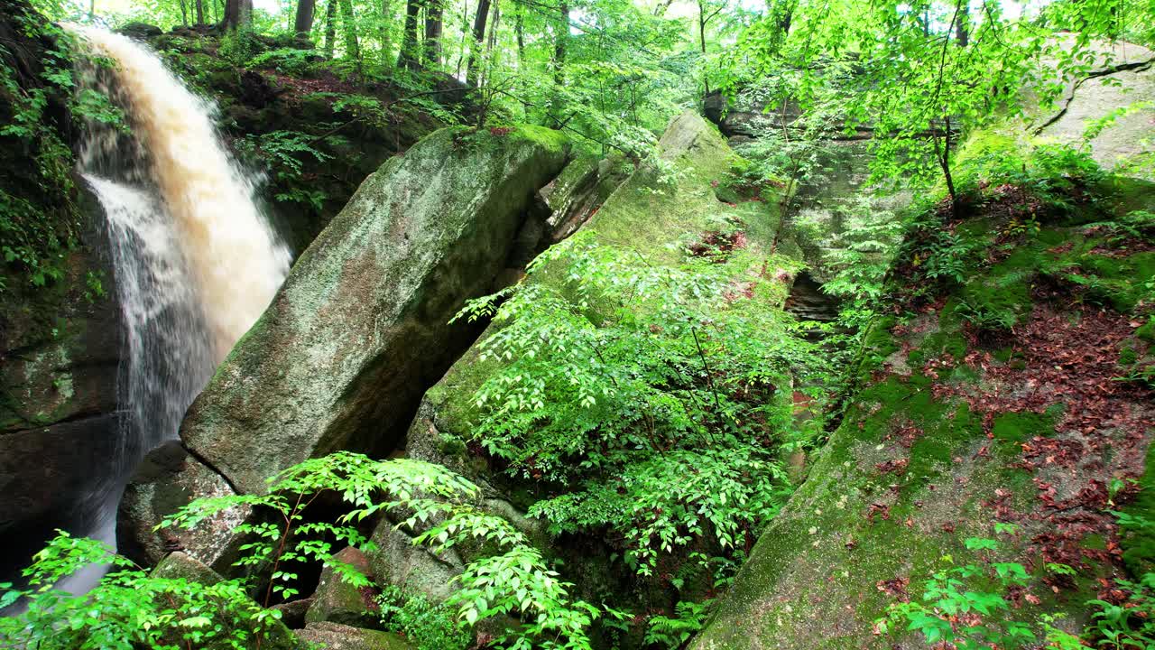 una toma de acercamiento de cascada cae entre hojas y rocas cubiertas de musgo en el parque estatal nelson ledges en un hermoso día de otoño