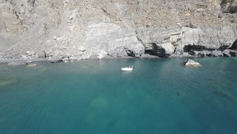 fpv drone diving over turquoise water and stunning rock formations of aspes black beach, south crete, greece