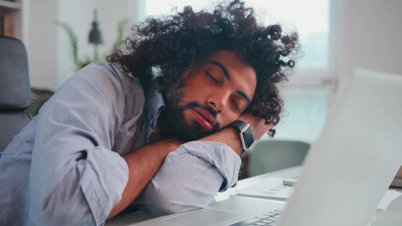 Young arabian man sleeps laying head around with laptop on office desk