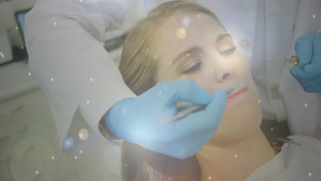manchas brillantes de luz que se mueven contra el dentista que trata a la paciente