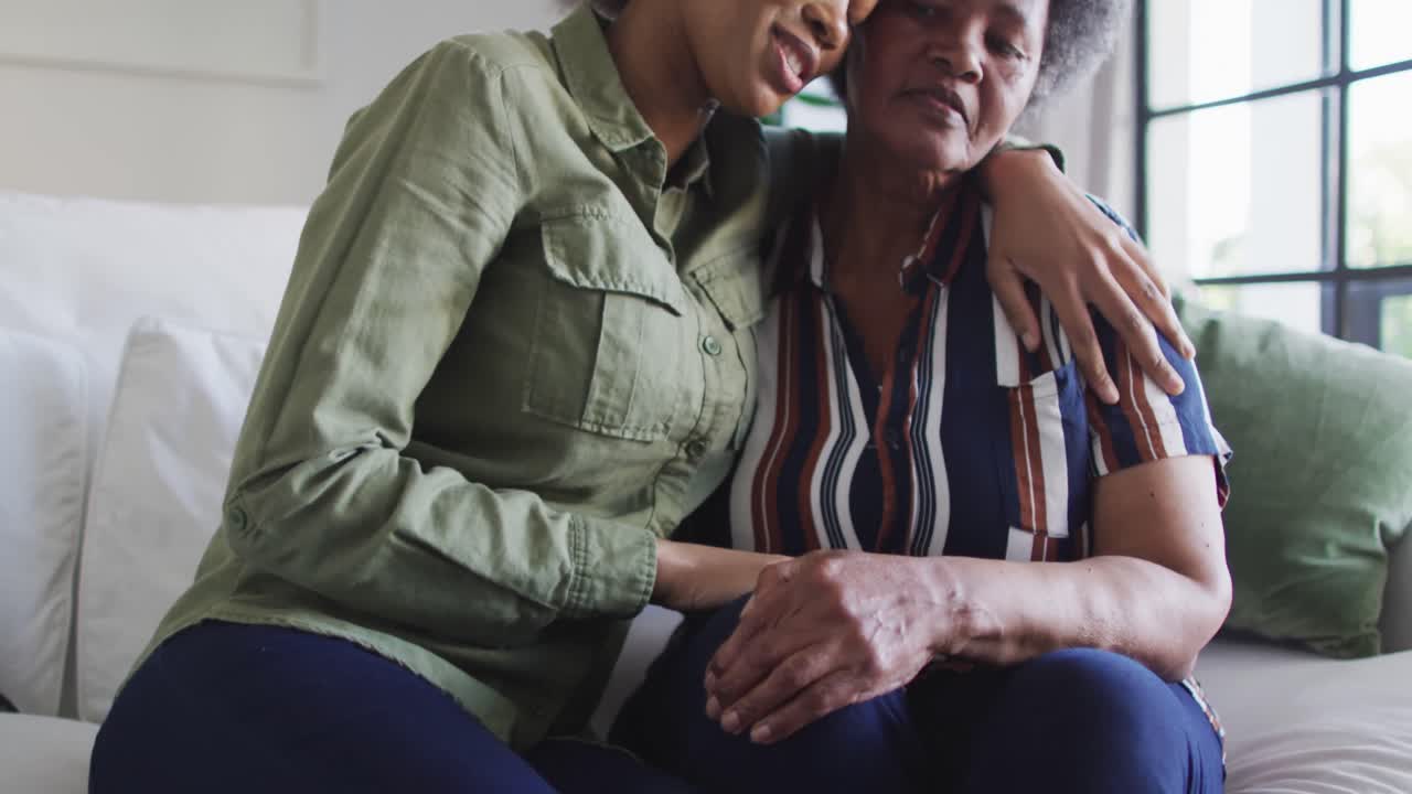 feliz hija adulta afroamericana y emocional madre mayor abrazando en casa, cámara lenta