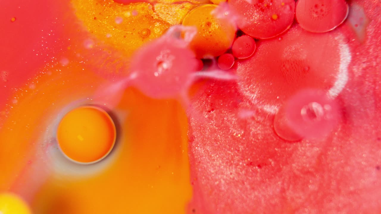 Inchiostro liquido rosso e arancione in un motivo astratto, bolle che scoppiano.