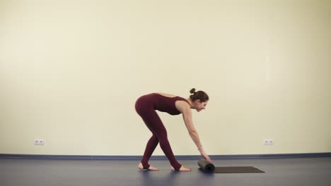 Young-attractive-woman-with-flexible-and-fit-body-starts-yoga-practise-on-a-black-mat