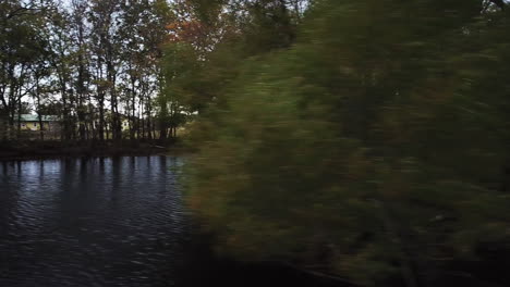 aerial drone pan shot flying over a lake surrounded by trees on a windy day